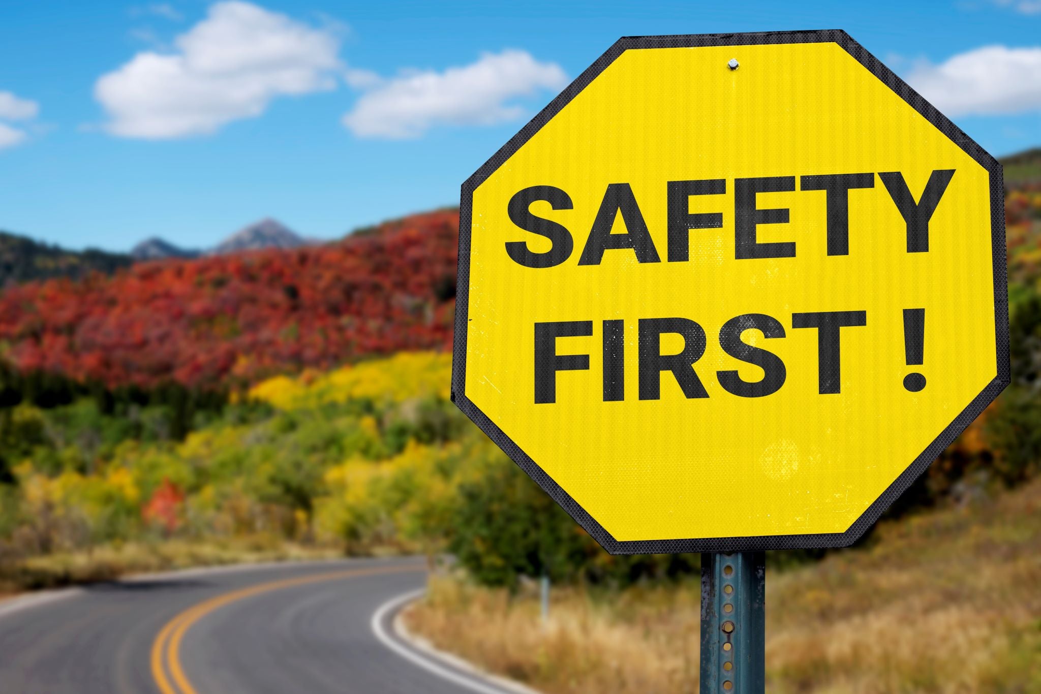 safety first sign next to a winding road