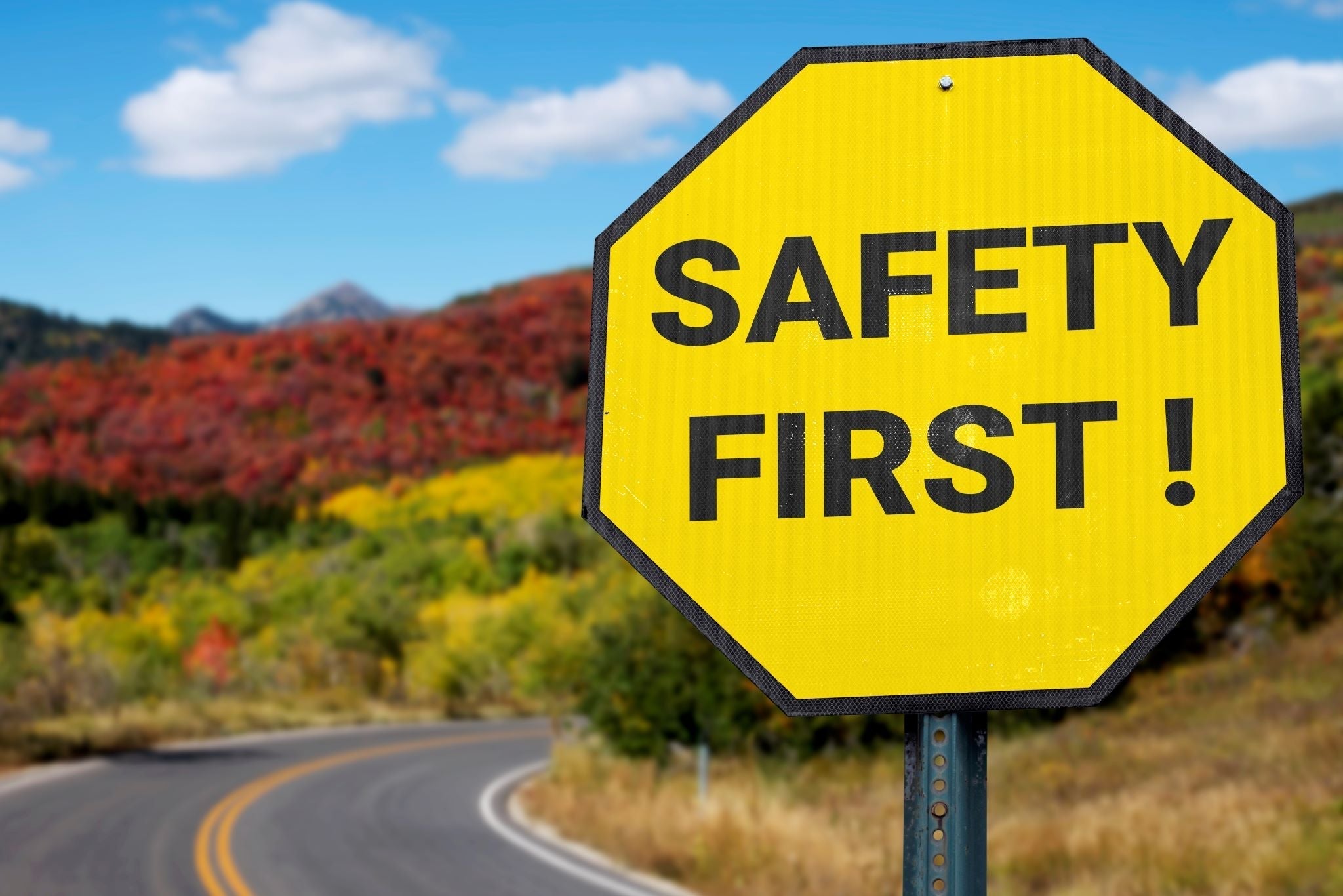 safety first sign next to a winding road
