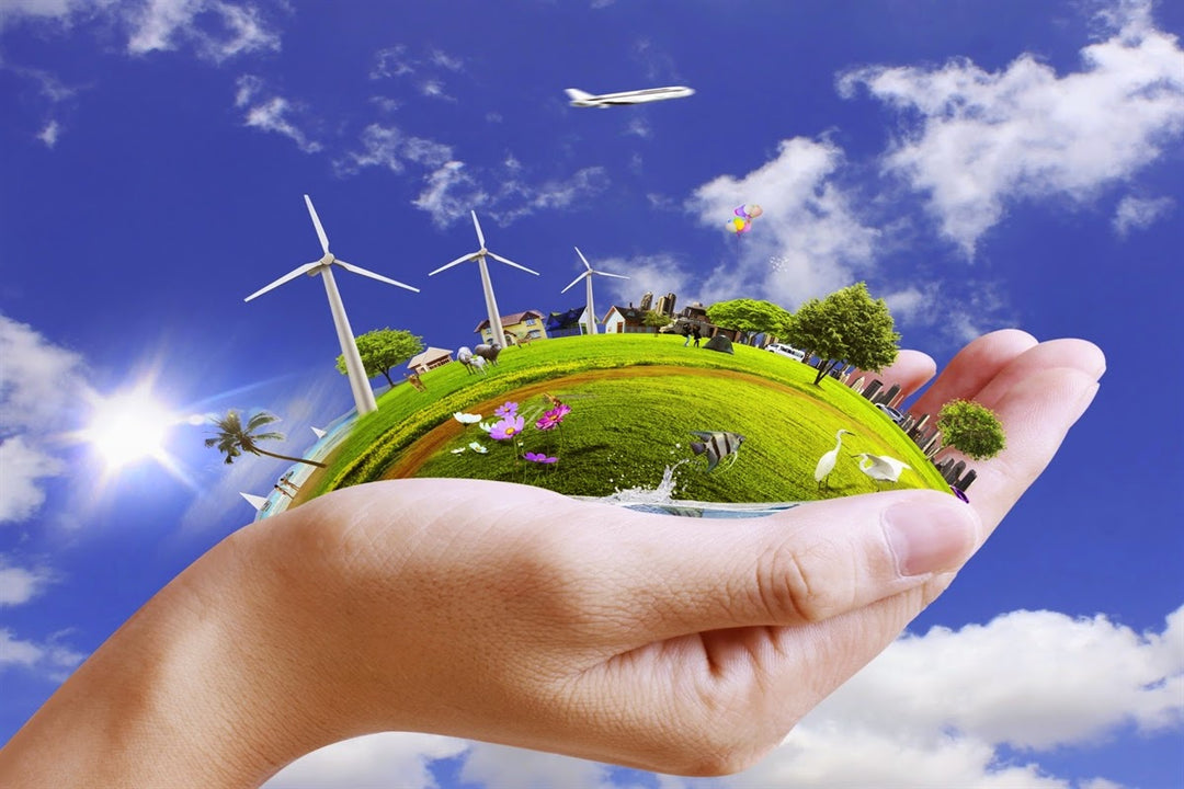 Hands holding sustainable land with windmills and trees.